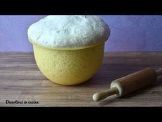 a yellow bowl filled with white powder next to a rolling pin on a wooden table