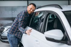 a man leaning on the door of a white car