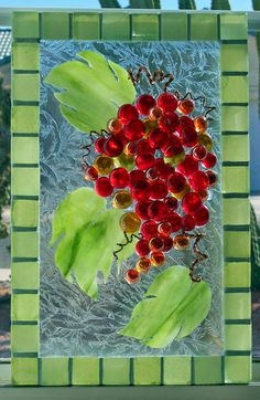 a glass plate with some red berries and green leaves on the outside, in front of a window