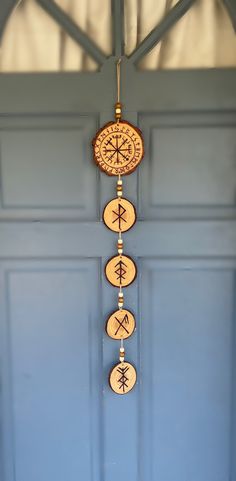 a wooden wind chime hanging from the side of a blue door with arrows on it