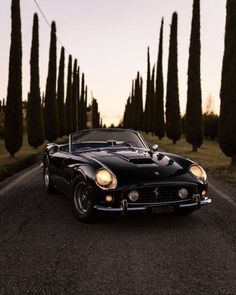 an old black sports car is parked on the side of the road