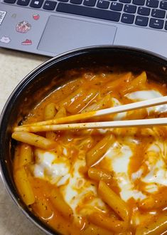 a pan filled with food next to a laptop