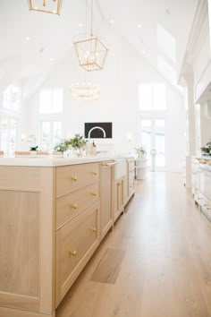 a large kitchen with an island and chandelier hanging from it's ceiling