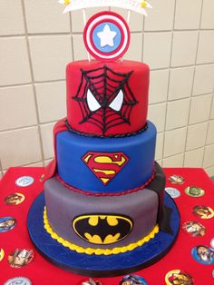 a three tiered cake decorated with superhero symbols