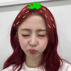 a girl with red hair has her eyes closed and is wearing a green leaf on top of her head