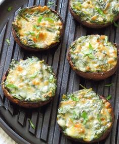 four mini pizzas with cheese and spinach toppings on a grilling pan