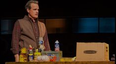 a man standing next to a table filled with bottles and cans on top of it