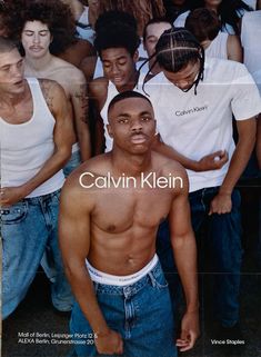 a group of men standing next to each other in front of a poster with the caption calvin klein