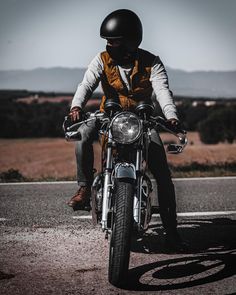 a man riding on the back of a motorcycle down a road