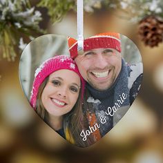 a heart shaped ornament hanging from a christmas tree with pine cones in the background