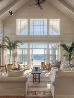 a living room filled with furniture and large windows next to the ocean in front of it