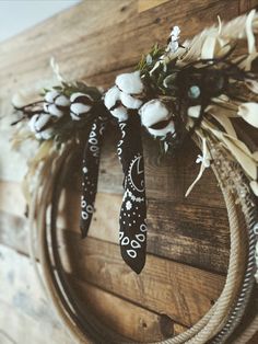 a wreath hanging on the side of a wooden wall decorated with cotton flowers and ribbons