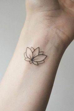 a small tattoo on the wrist of a woman with a lotus flower in its center