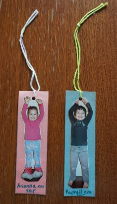 two bookmarks with children's pictures hanging from them on a wooden table top