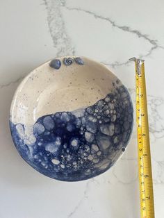 a blue and white bowl sitting next to a ruler