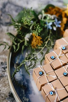 some brown boxes with blue eyes are on a plate next to flowers and greenery