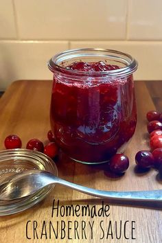 homemade cranberry sauce in a glass jar and spoon on a wooden table next to it