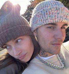 a man and woman wearing beanies are posing for a photo together in the sun