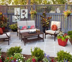 an outdoor seating area with potted plants and flowers on the side of the fence