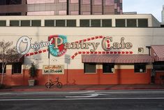 the outside of a restaurant called pantry cafe with bicycles parked in front and an orange building behind it