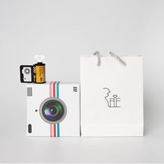 a white bag with a camera next to it on top of a box and some other items