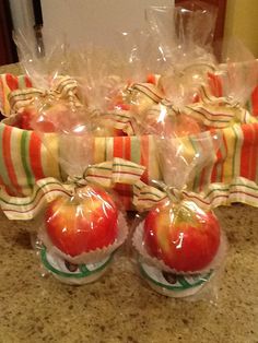 apples wrapped in cellophane and sitting on a counter with candy bags around them