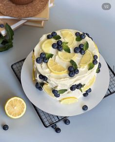 a cake with lemons, blueberries and mint leaves on it sitting on a plate