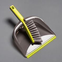 a dustpan with a yellow handle and a large brush on the top of it