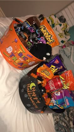 two buckets filled with halloween candy on top of a bed