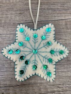 a snowflake ornament hanging from a string on a wooden table with beads