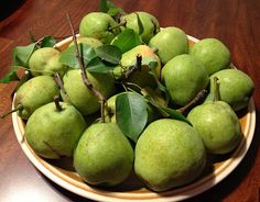 a plate filled with green apples on top of a wooden table