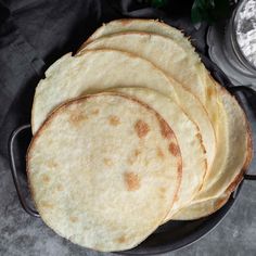 four tortillas sitting on top of a black plate