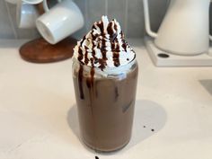 there is a chocolate drink with whipped cream on top and drizzled in the liquid