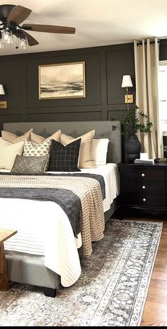 a bedroom with a bed, nightstands and rug on the wooden floor next to two windows