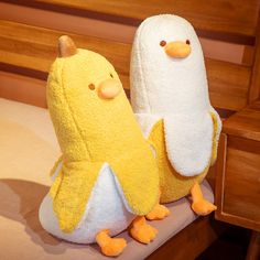 two yellow and white stuffed animals sitting on a bed next to each other in front of a wooden headboard