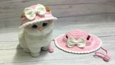 a crocheted cat is next to a hat and leash on a wooden floor