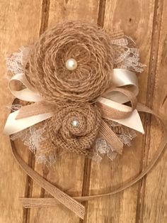 a close up of a flower on top of a wooden table with ribbon and pearls