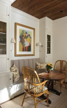 a living room with a couch, table and chairs next to a painting on the wall