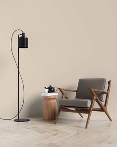 a chair, lamp and table in a room with wood flooring on the side