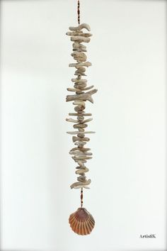 a sea shell hanging from a string with rocks and shells attached to it's sides