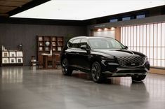 a black suv is parked in a large room with wooden shelves and windows behind it