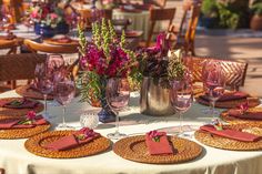 the table is set with place settings and flowers in vases on top of them