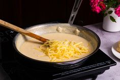 a pan filled with cheese sitting on top of a stove next to a plate of food