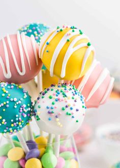 colorful cake pops with sprinkles and candies in a clear glass vase