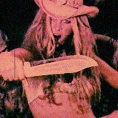 a woman holding a knife in her right hand and wearing a hat on top of her head