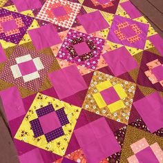 a pink and yellow patchwork quilt on a wooden deck