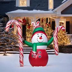 a large inflatable snowman with candy canes on the front lawn of a house