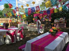 there are many colorful decorations on the tables and chairs in this backyard party setting that is decorated with paper flowers, tissue pom poms, streamers, and lanterns