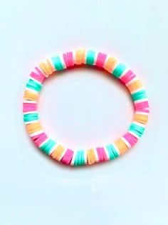 a bracelet made out of multicolored plastic beads on a white surface with a black bead in the middle