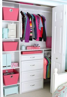 a white closet with pink and blue bins filled with clothes on top of it